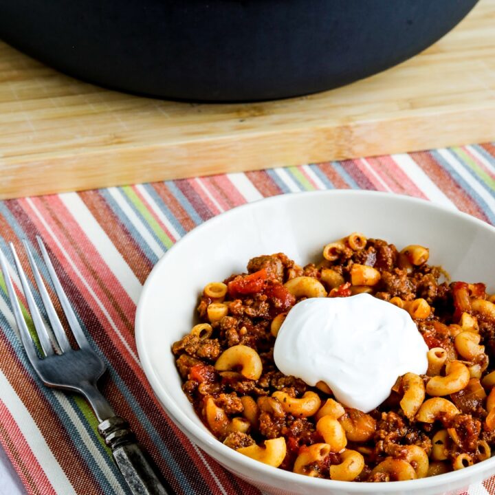 Better-than-Mom's Hamburger Goulash showing one serving in bowl with pan of Goulash in back.