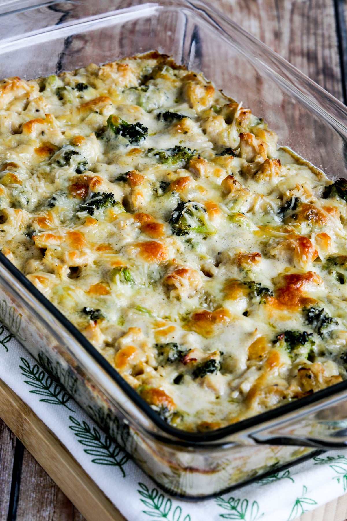 Chicken Broccoli Alfredo Casserole show in baking dish on napkin and cutting board.