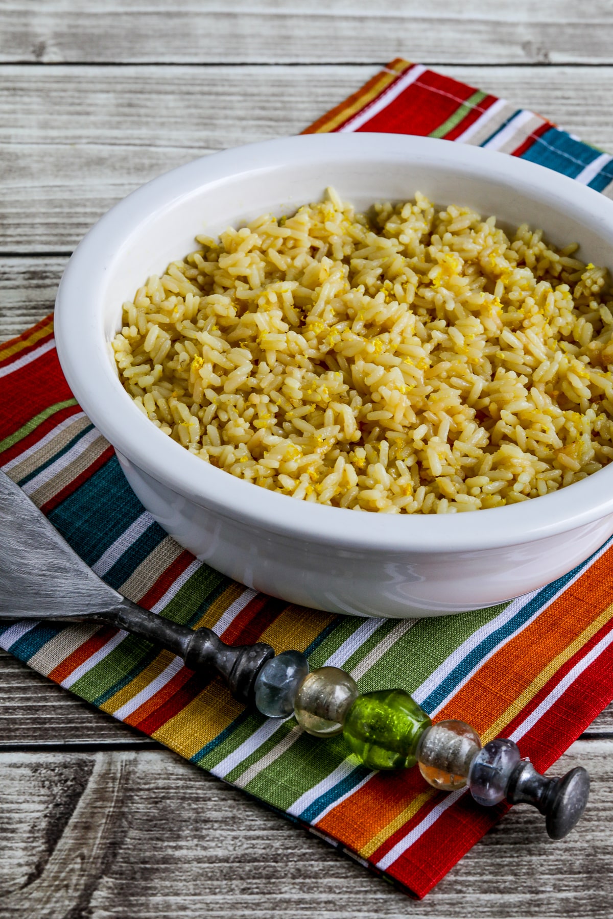 Greek Lemon Rice shown in bowl with serving spoon.