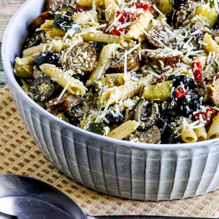 Pasta Salad with Sausage, Zucchini, Olives, and Peppers shown in serving bowl with forks and napkin