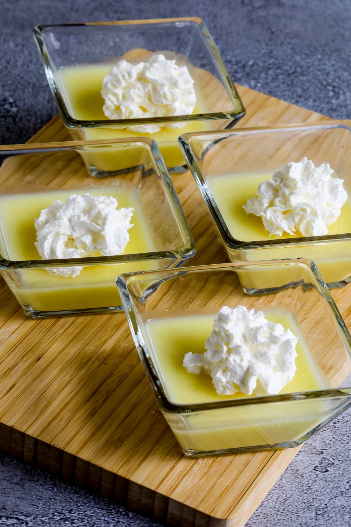 Sugar-Free Jelled Ricotta Pudding shown in four serving dishes with whipped cream on top.