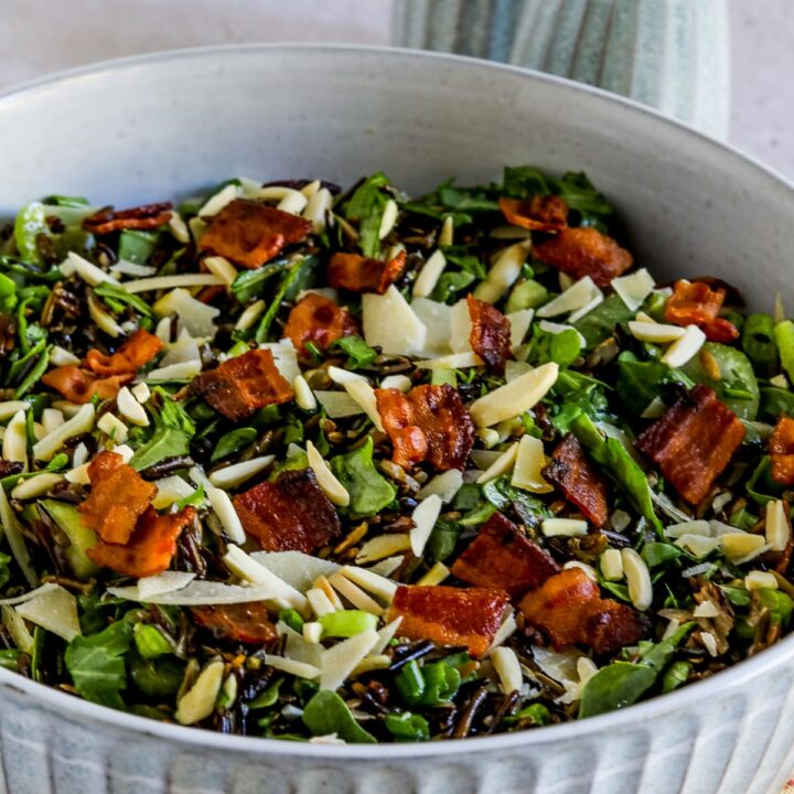 Wild Rice Salad with Bacon and Arugula shown in bowl with salt-pepper in back.