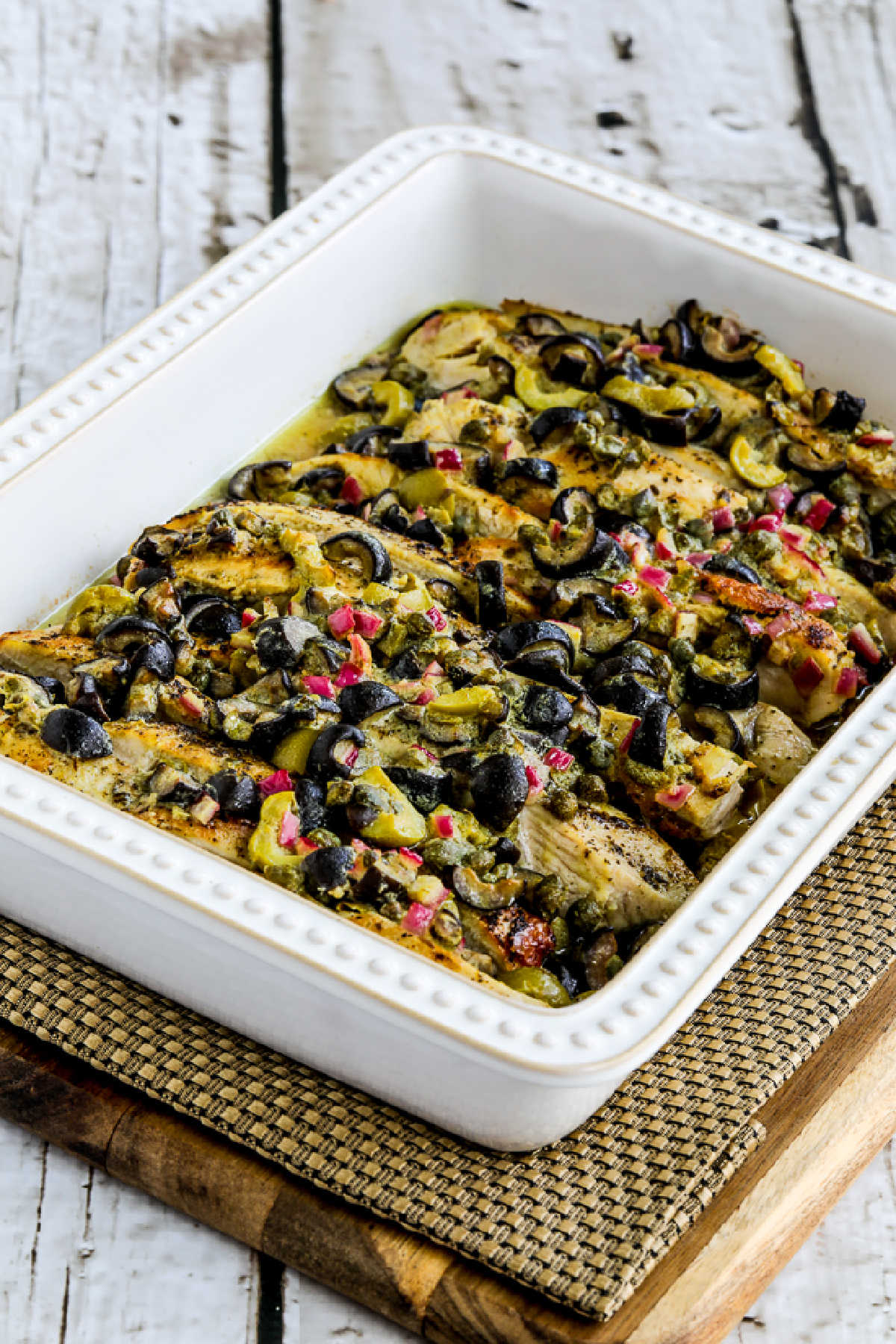 Chicken Bake with Olive and Caper Sauce shown on napkin on cutting board