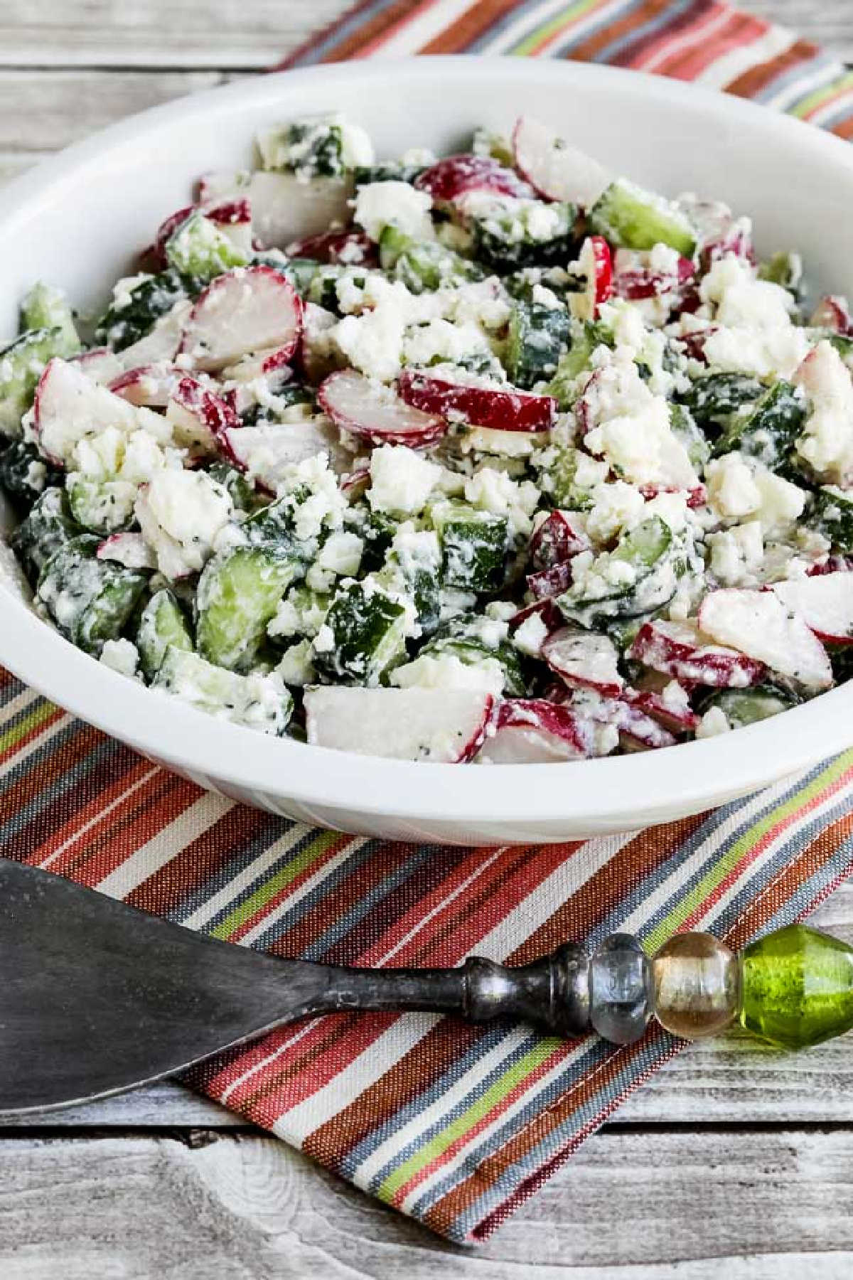 Cucumber Radish Salad in serving bowl with green fork and striped napkin