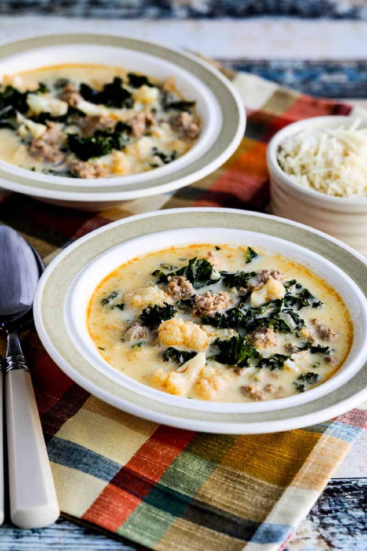 farther away photo of Instant Pot Zuppa Toscana Soup shown in two bowls with Parmesan