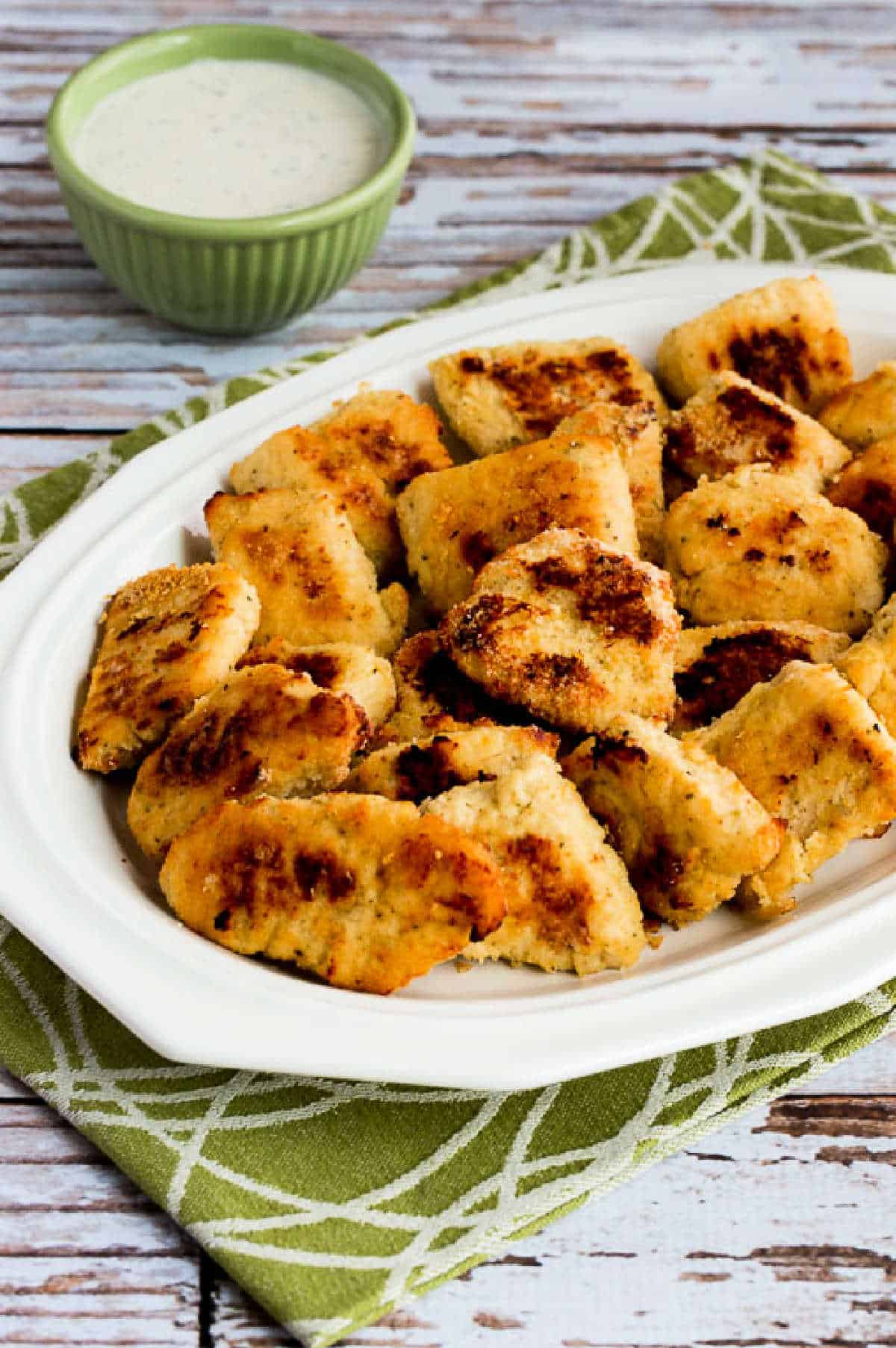 baked chicken nuggets on serving plate with green-white napkin and dipping sauce