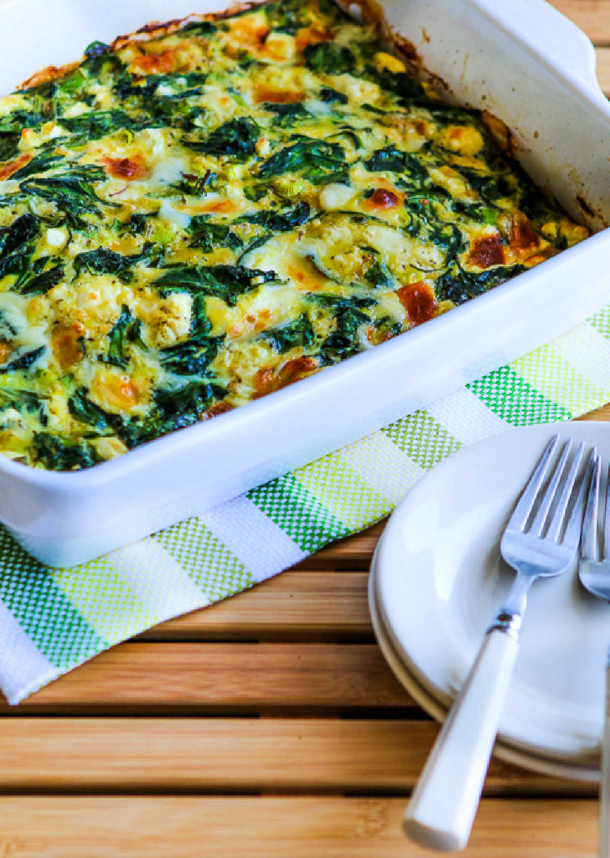 Power Greens Breakfast Casserole in baking dish with plates-forks in front