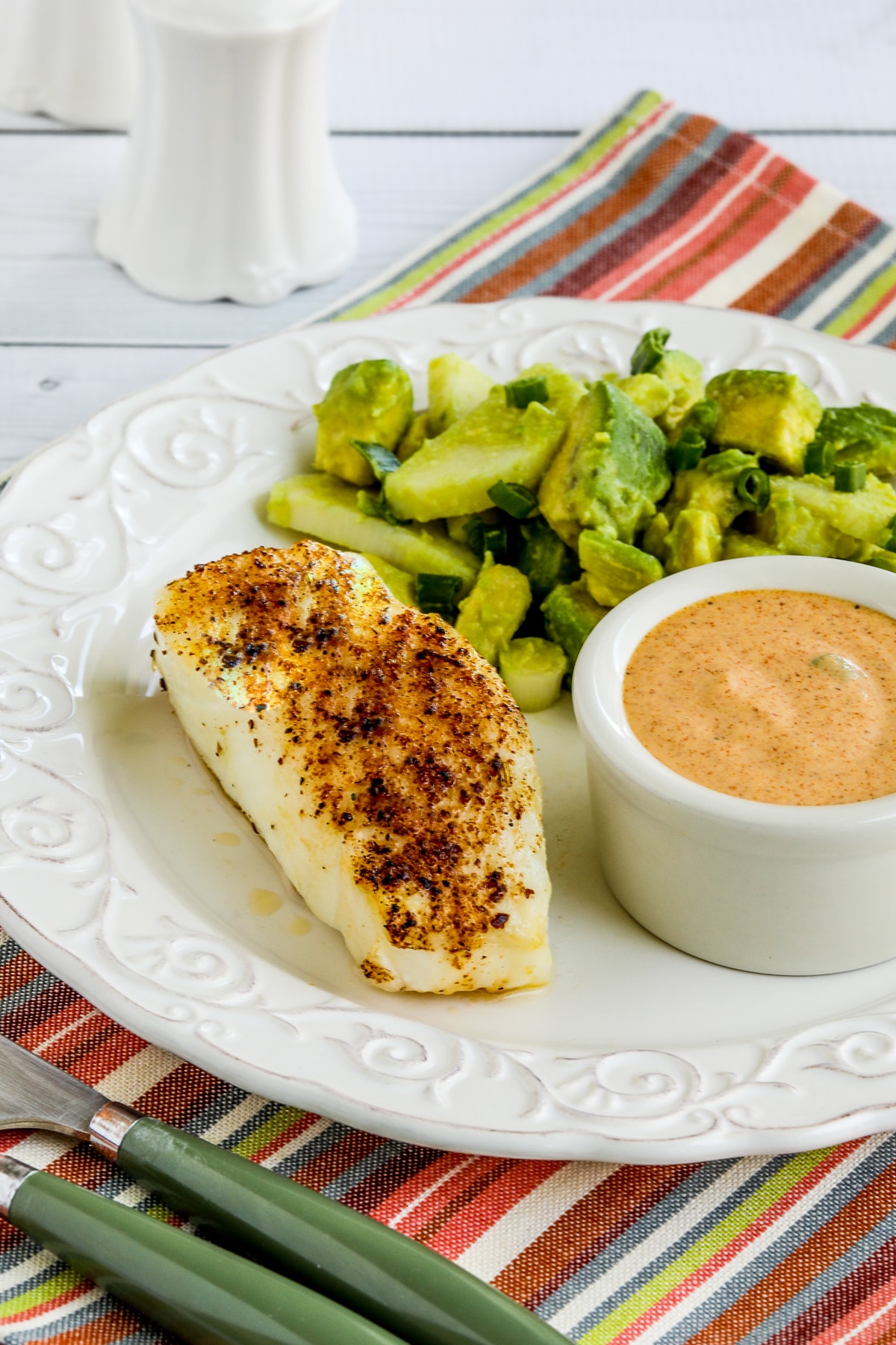 Spicy Air Fryer Fish shown on plate with avocado salad and remoulade sauce