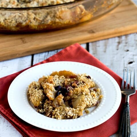 Cranberry Apple Crumble finished crumble in baking dish with one serving on plate