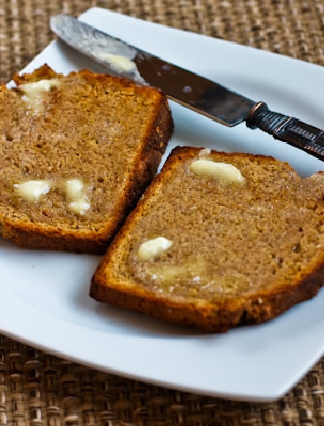 Brown Irish Soda Bread shown on serving plate with knife and butter melting