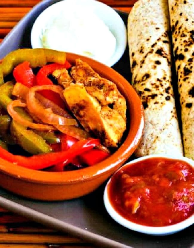 Slow Cooker Chicken Fajitas on plate with low-carb tortillas, sour cream, and salsa.