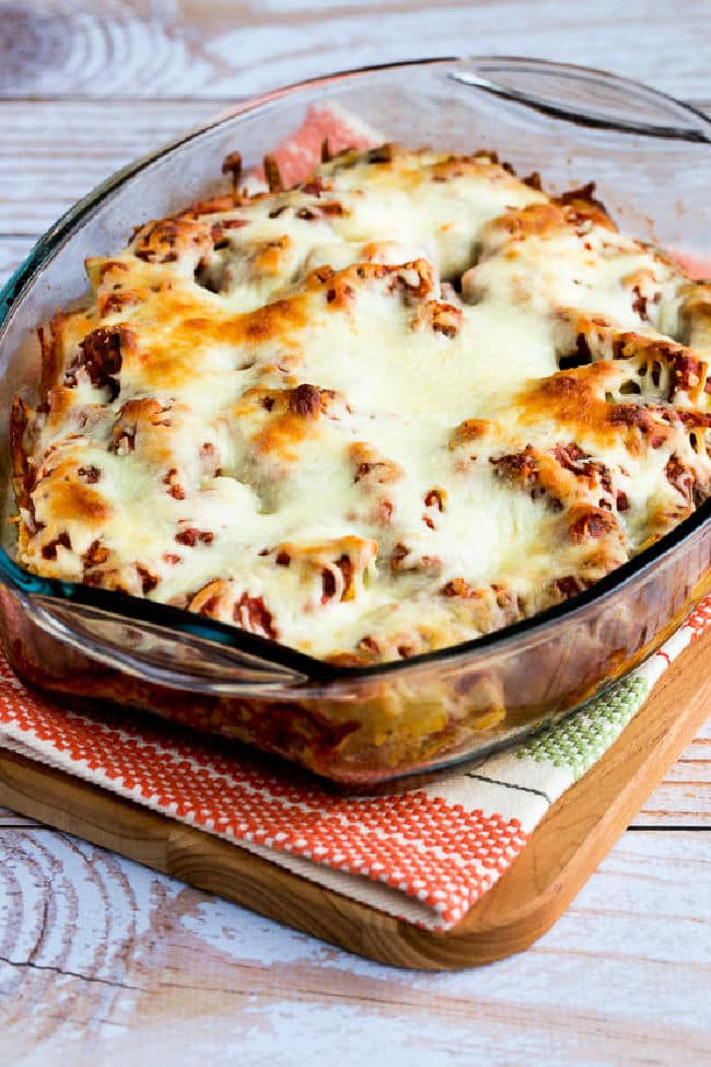 Meatball Casserole with Artichokes shown in baking dish on cutting board and napkin.