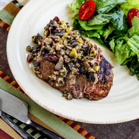 Pan-Grilled Steak with Olive Sauce photo of cooked steak with salad on serving plate