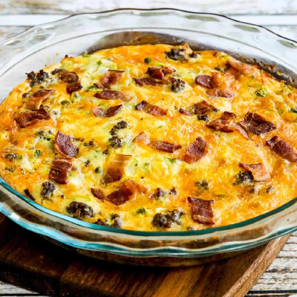 Bacon Cheeseburger Keto Breakfast Quiche shown in glass baking dish on cutting board