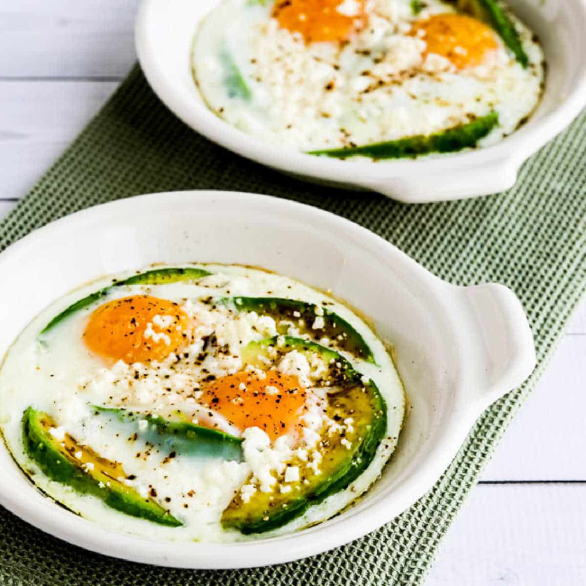 Square image of Baked Eggs with Avocado and Feta shown in individual baking dishes.