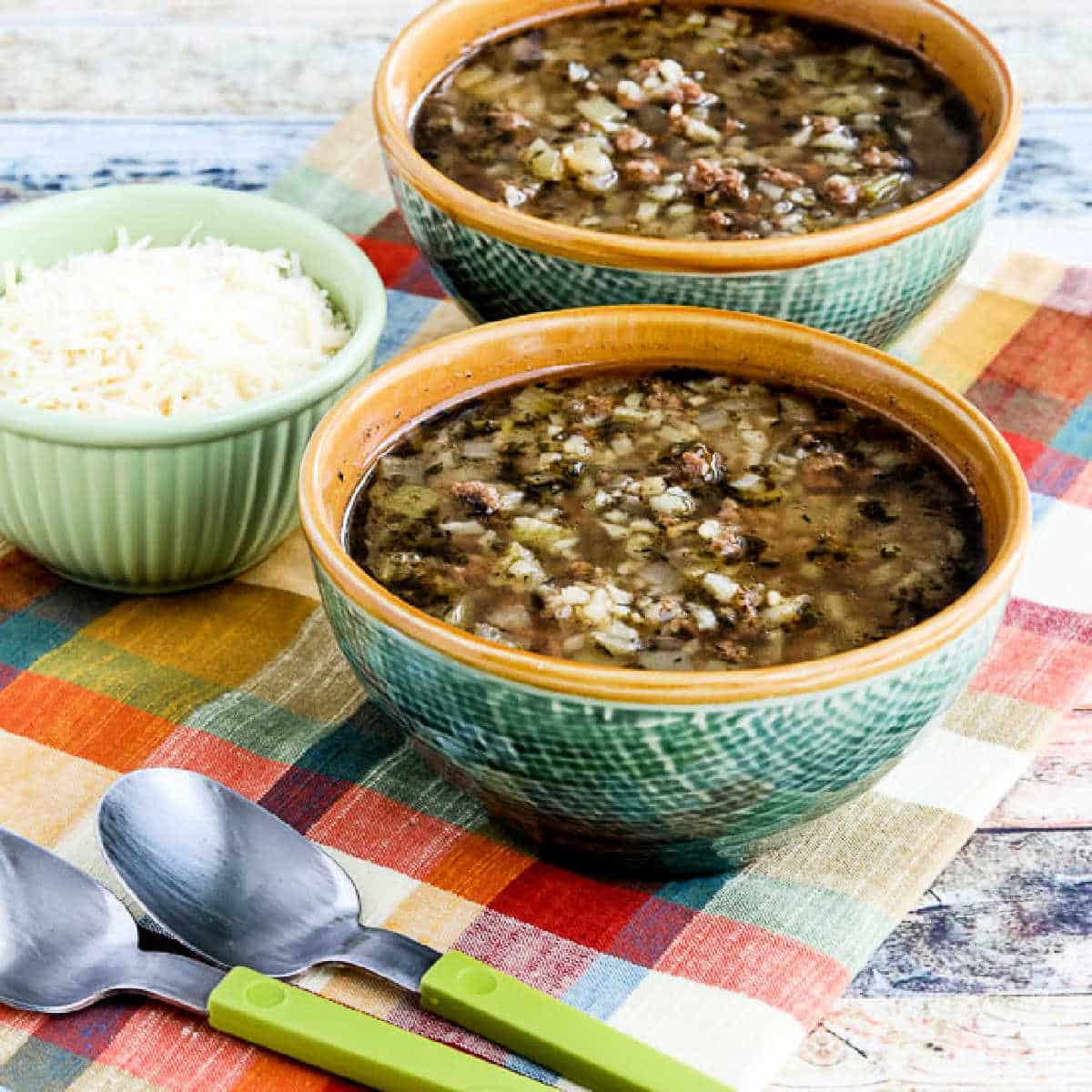 Square image for Instant Pot Ground Beef Cauliflower Soup in two bowls with Parmesan on the side.