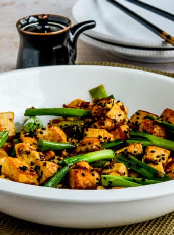 Square image for Stir-Fried Tofu with Ginger And Soy Sauce shown in serving bowl with soy sauce dispenser and chopsticks in back.