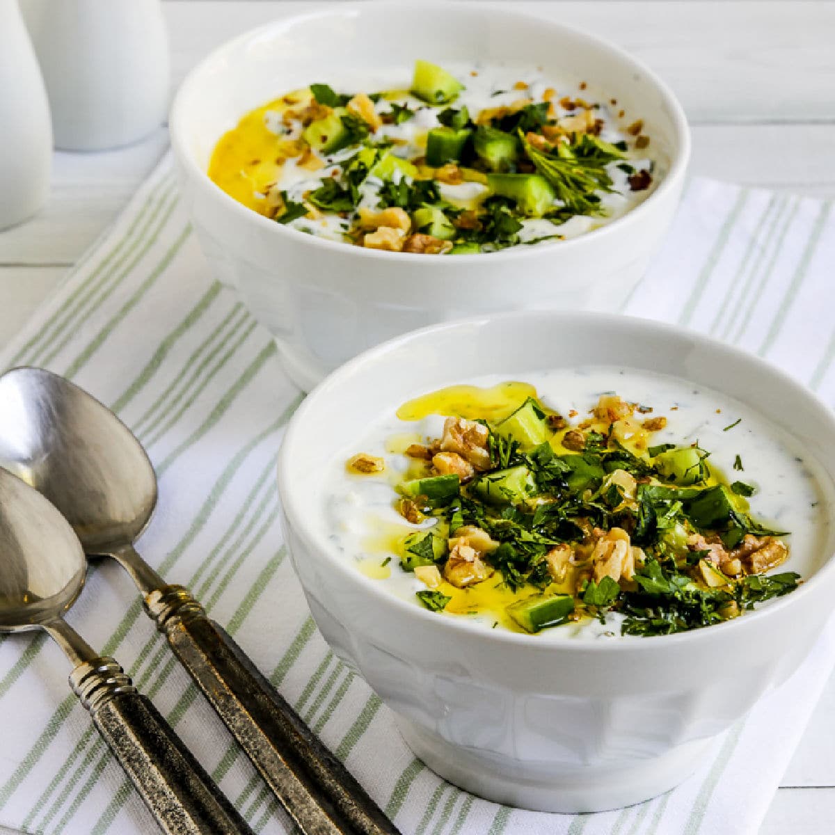 Square image of Tarator (Chilled Cucumber Yogurt Soup) shown in two serving bowls.