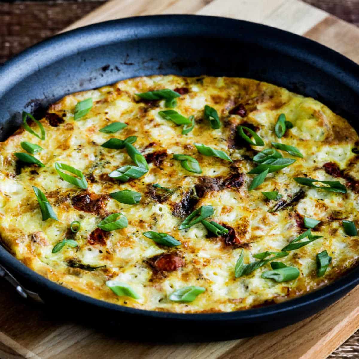 Square image for Asparagus Tomato Frittata shown in pan on cutting board.