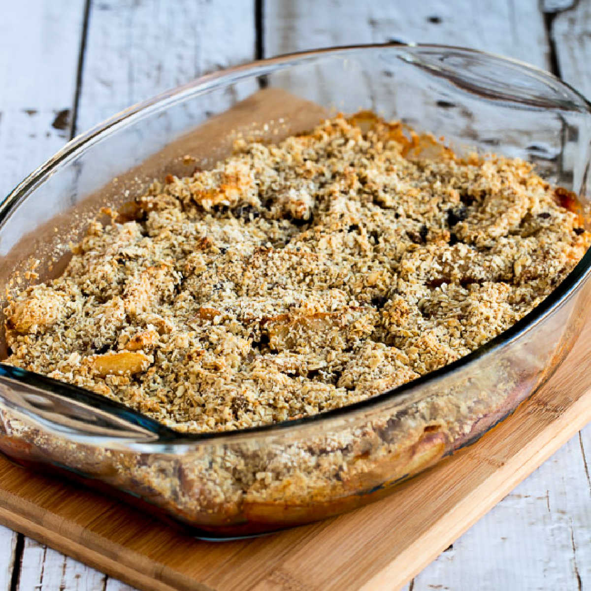 square image of Cranberry Apple Crumble shown in baking dish on cutting board