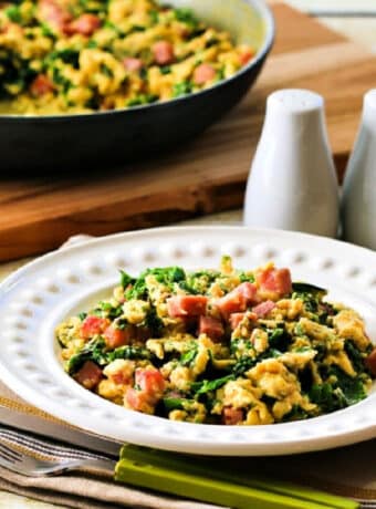 Square image for Green Eggs and Ham Recipe shown in serving bowl with frying pan in back.