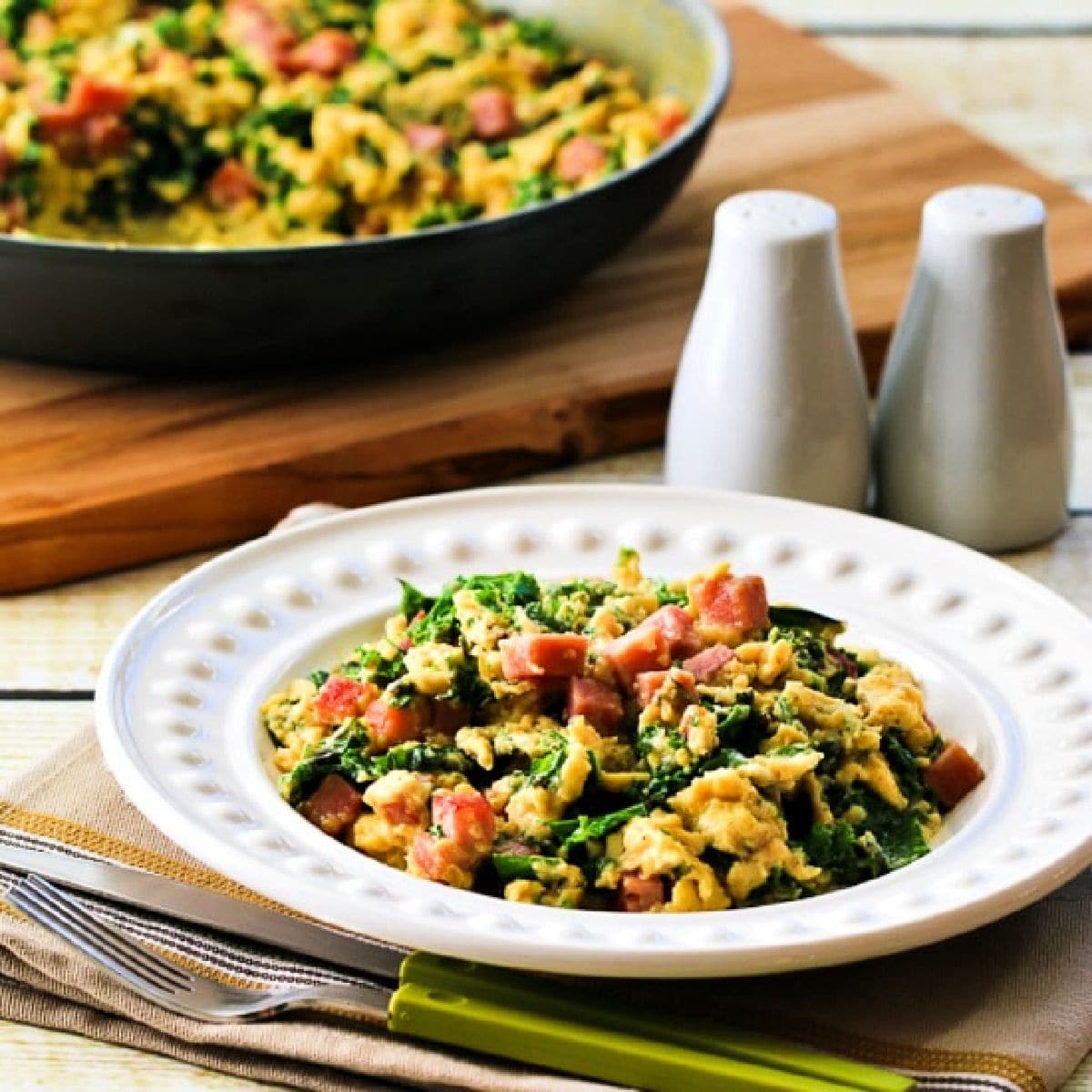 Square image for Green Eggs and Ham Recipe shown in serving bowl with frying pan in back.