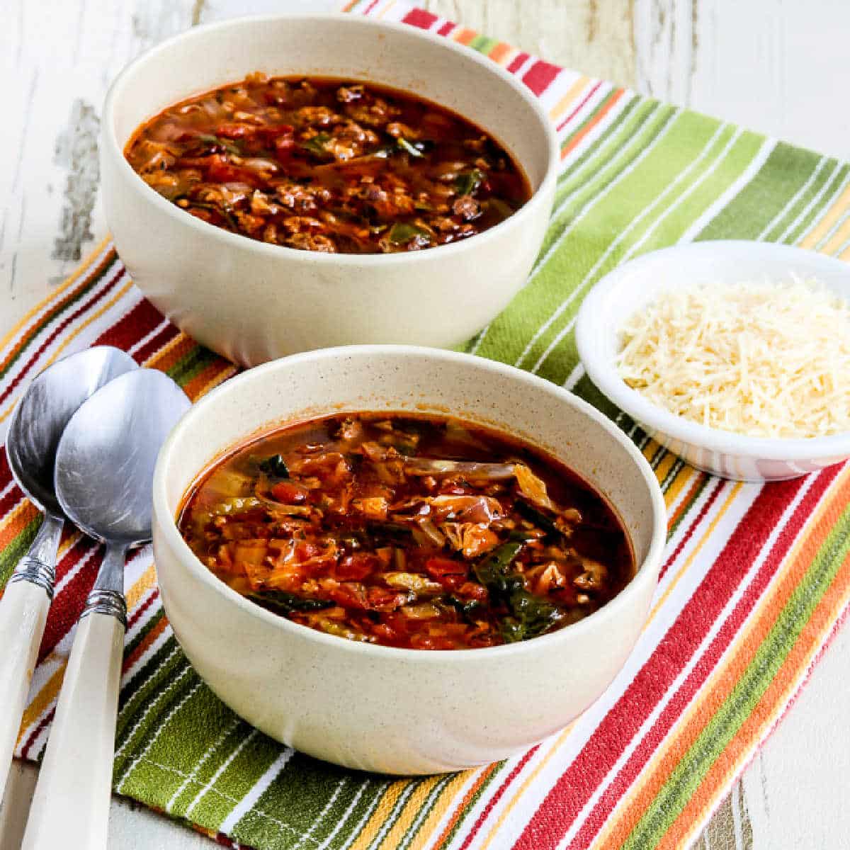 Square image for Ground Beef Vegetable Soup shown in two bowls with Parmesan cheese.