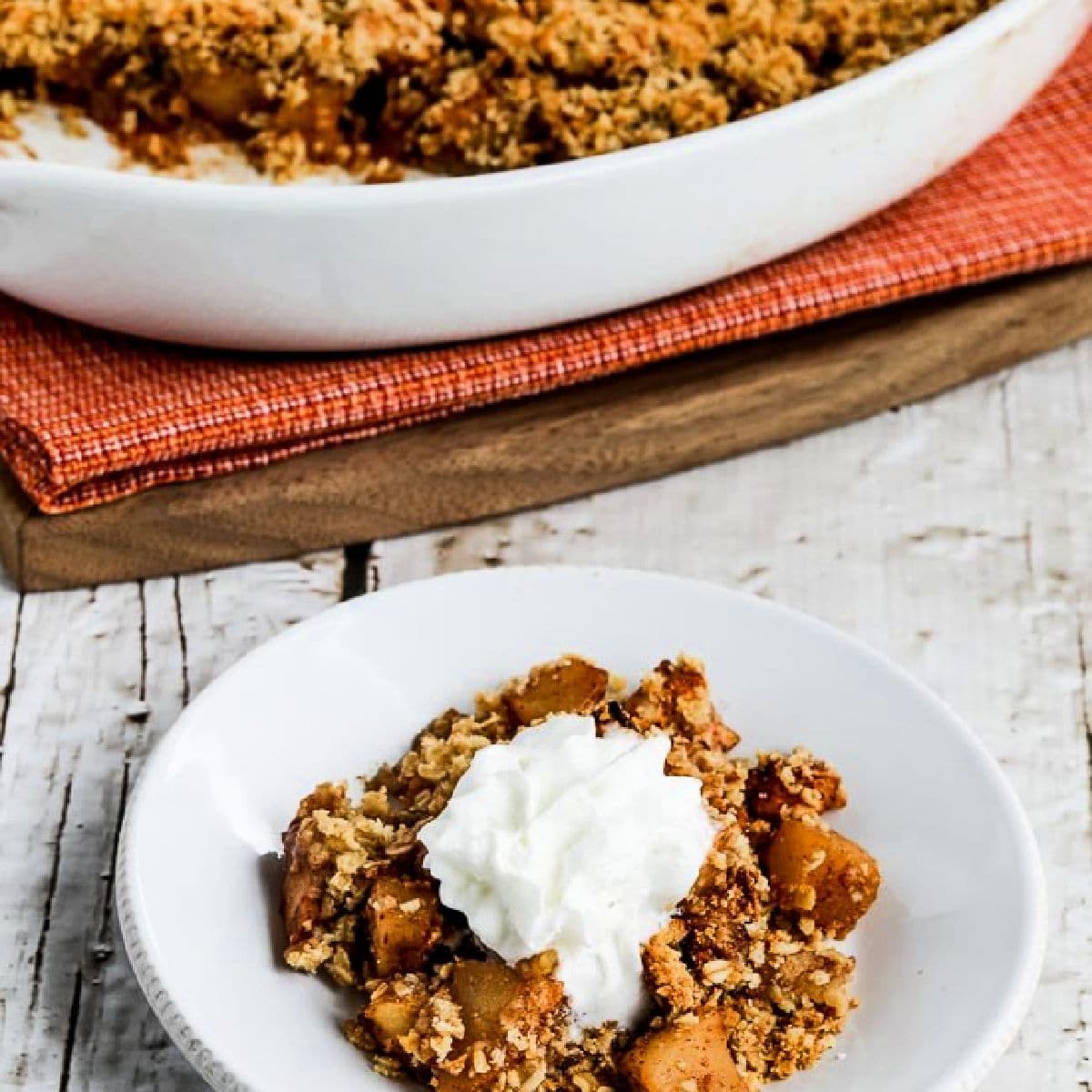 Square image for Low-Sugar Apple Crisp with one serving on plate and baking dish in back.