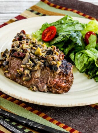 Square image for Pan-Grilled Steak with Olive Sauce shown on plate with lettuce and tomato salad.