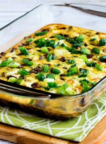 Square image for Sausage, Mushrooms, and Feta Baked with Eggs shown in baking dish on cutting board.