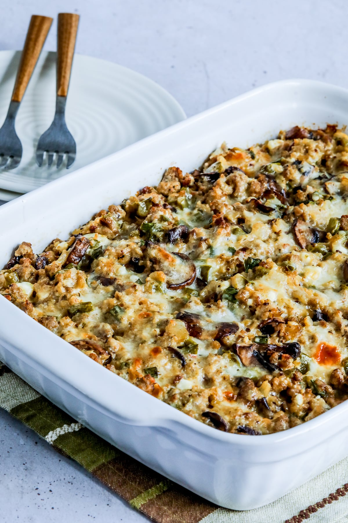 Ground Turkey Casserole with Cauliflower Rice in baking dish with plates, forks in back.