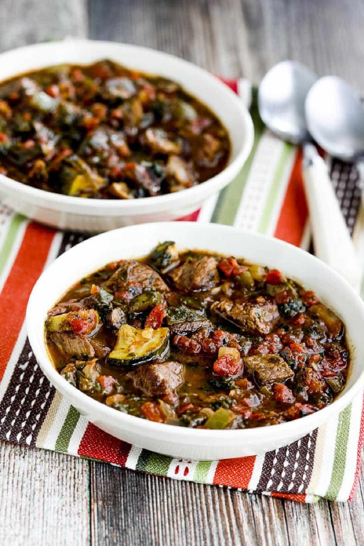 Italian Beef Stew with Zucchini, Mushrooms, and Basil shown in two serving bowls on striped napkin