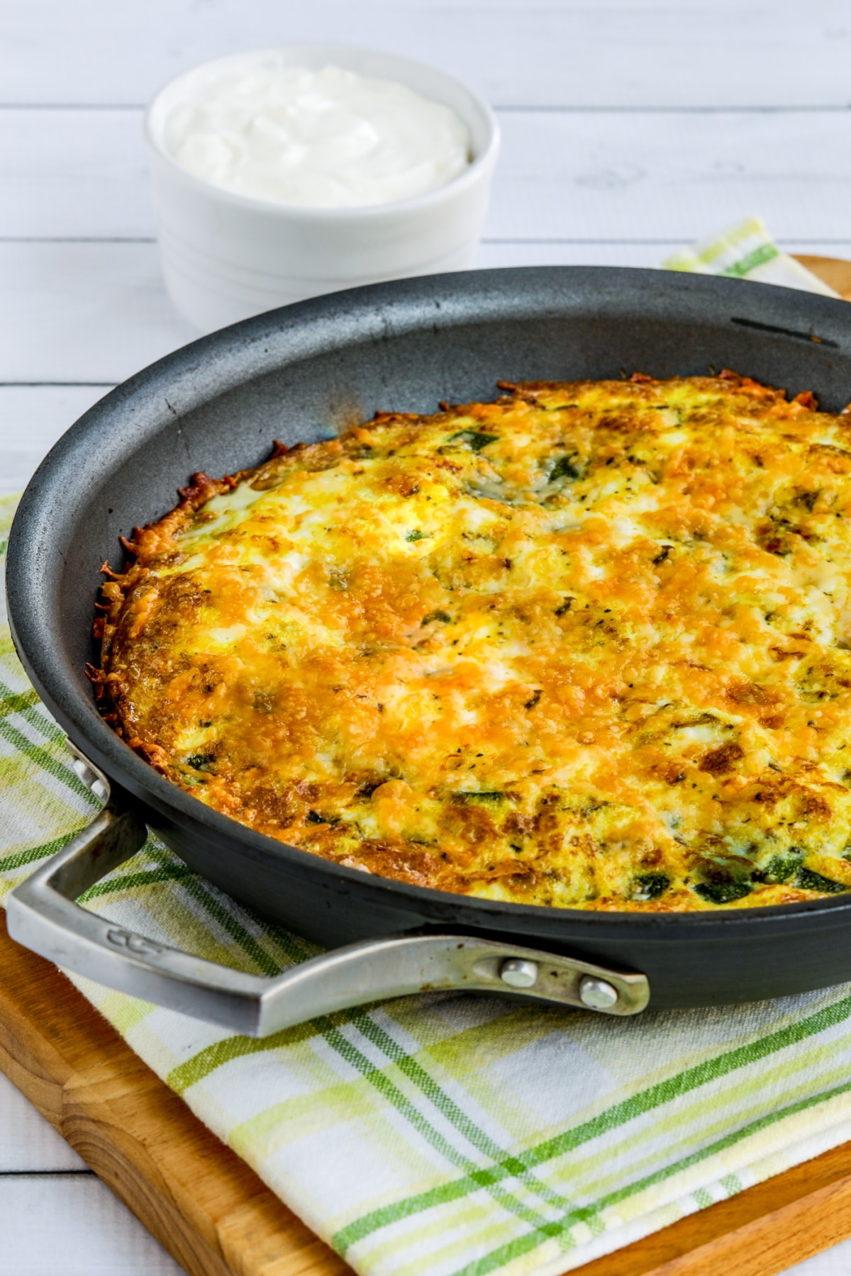 Zucchini Frittata in pan on cutting board with green and yellow napkin