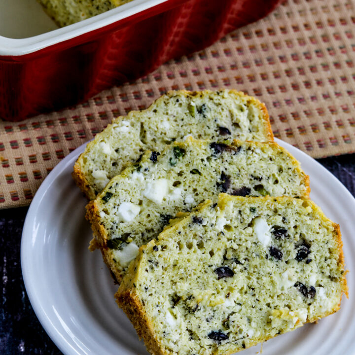 Olive Bread sliced on plate, with rest of loaf in background in baking dish