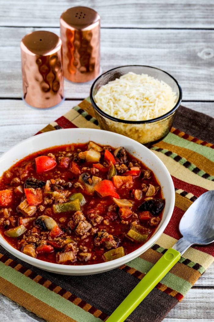 Italian Sausage Stew in serving bowl with spoon, salt-pepper shakers, and Parmesan