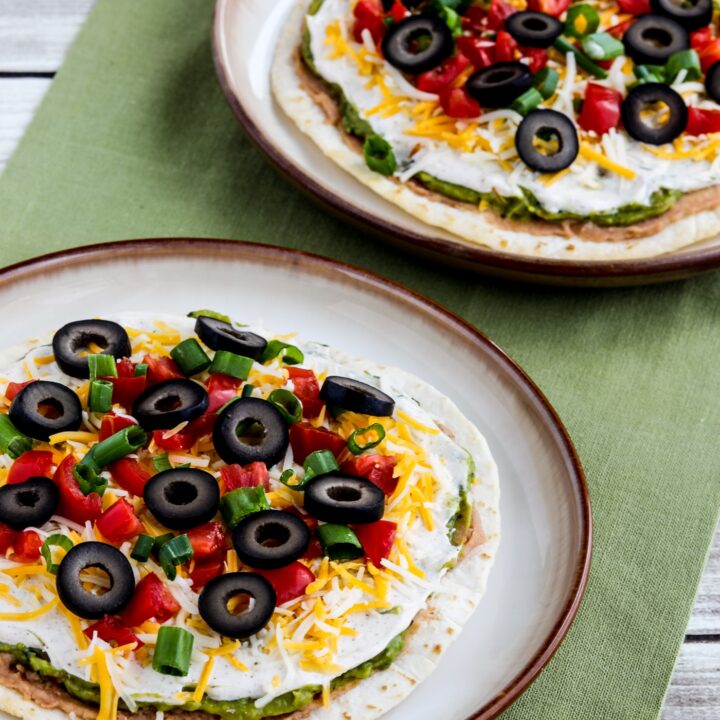 Seven Layer Dip Tostadas shown on two serving plates with green napkin