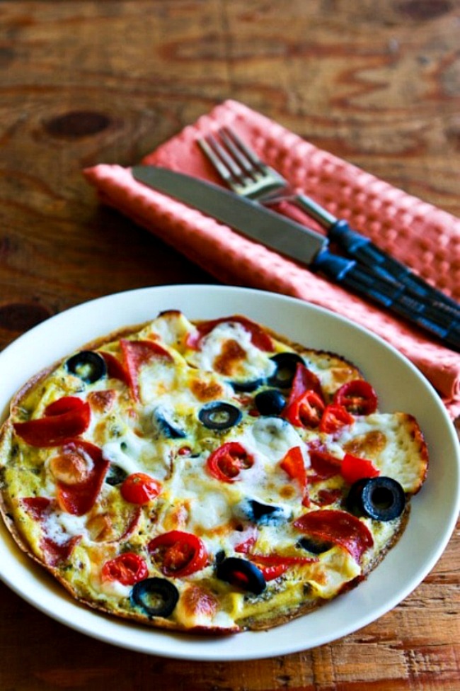 Egg-Crust Breakfast Pizza shown on plate with silverware in back