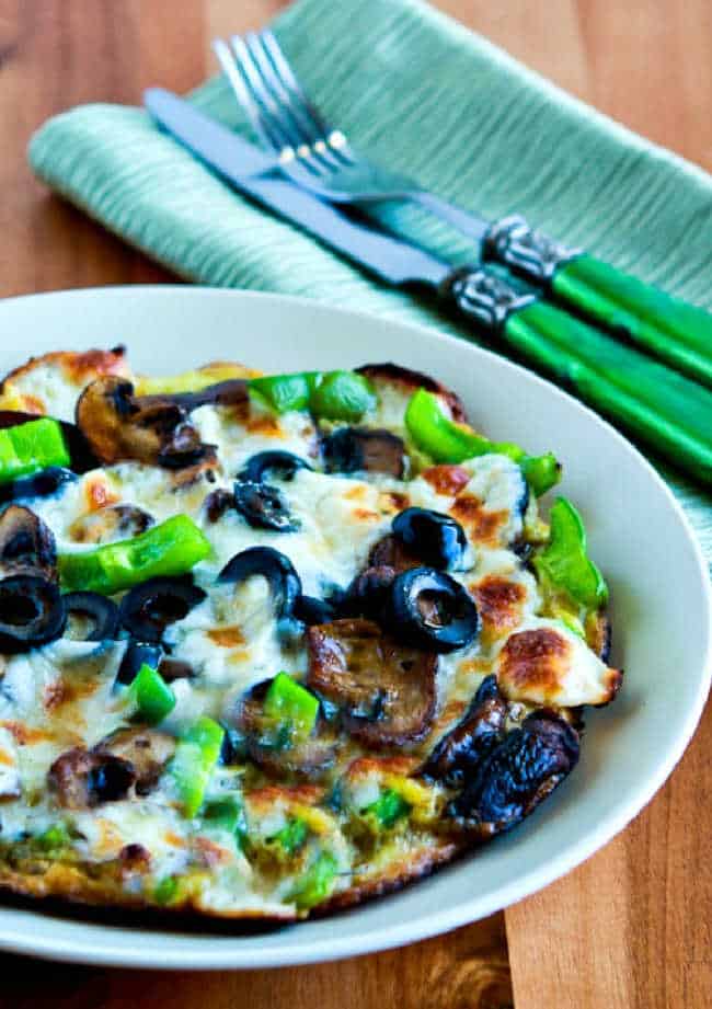 cropped photo of Egg-Crust Vegetarian Breakfast Pizza on plate with silverware in back