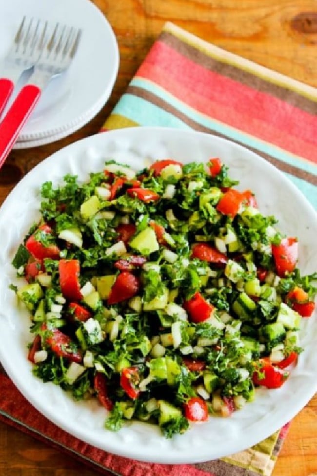 Middle Eastern Tomato Salad on serving plate with plates-forks in background