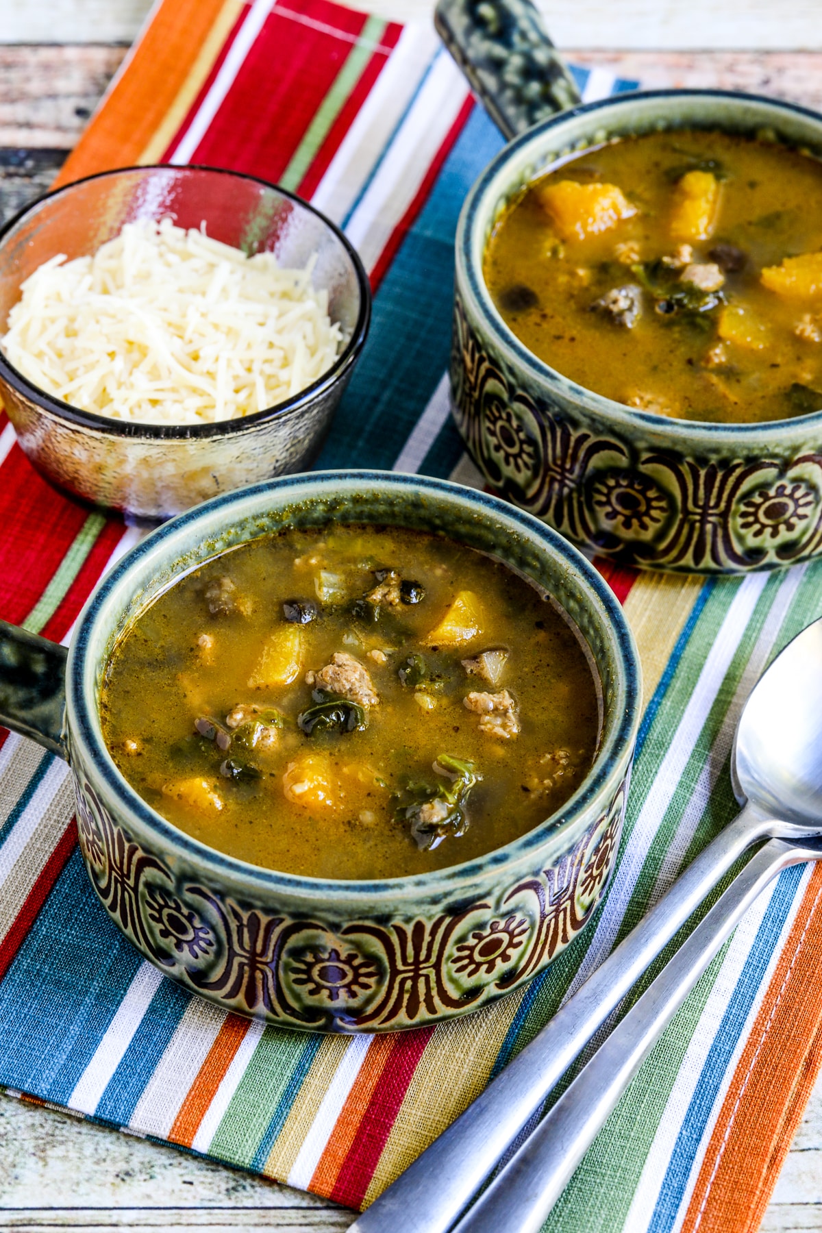 Turkey Soup with Kale, Mushrooms, and Butternut Squash shown in two bowls on striped napkin