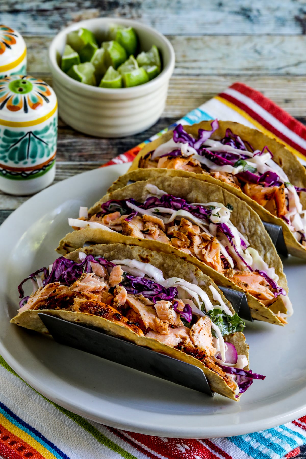 Salmon Tacos with Mexican Slaw shown in taco holder with limes on the side