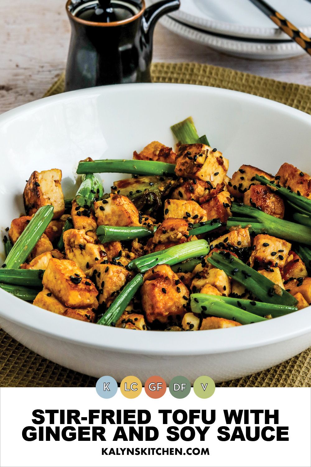 Pinterest image for Stir-Fried Tofu with Ginger and Soy Sauce shown in serving bowl with soy sauce and chopsticks in back.